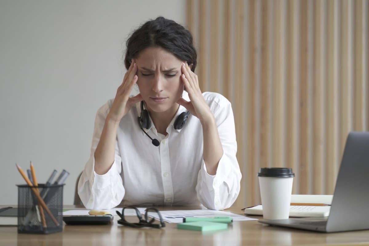 Stressed woman suffering from headache massaging temples while sitting