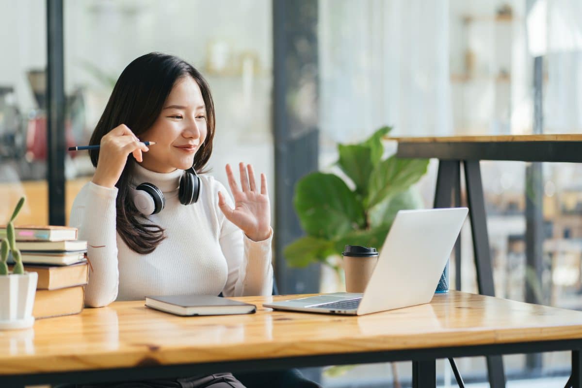 beautiful asian woman smiling and waving in a video conference