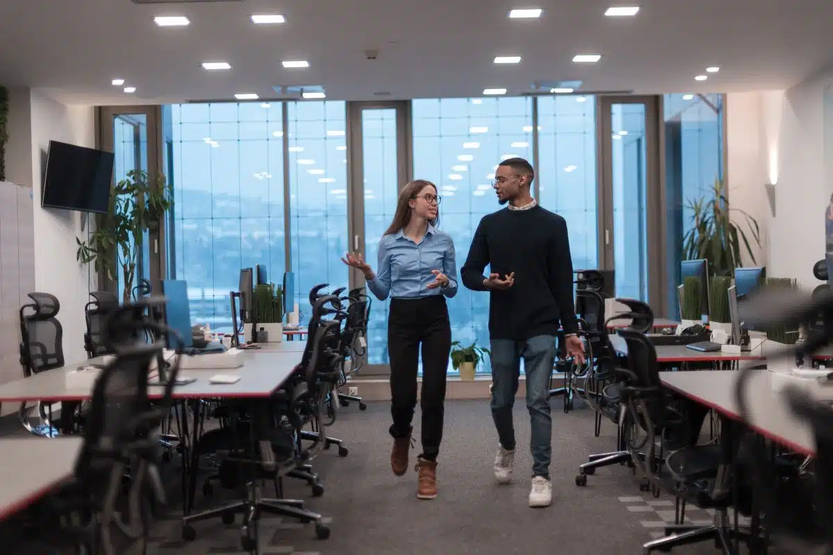man and woman talking while walking in a modern office