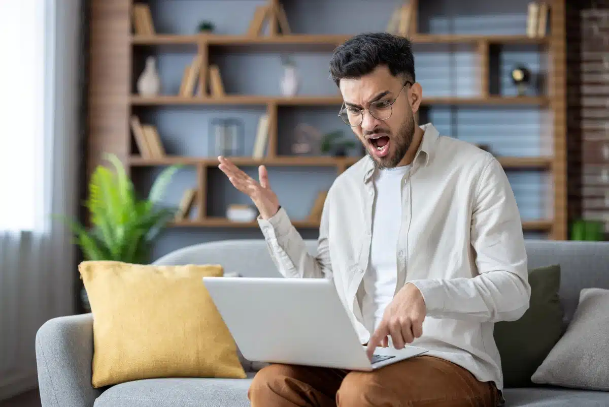 man with shocked look on his face while using laptop