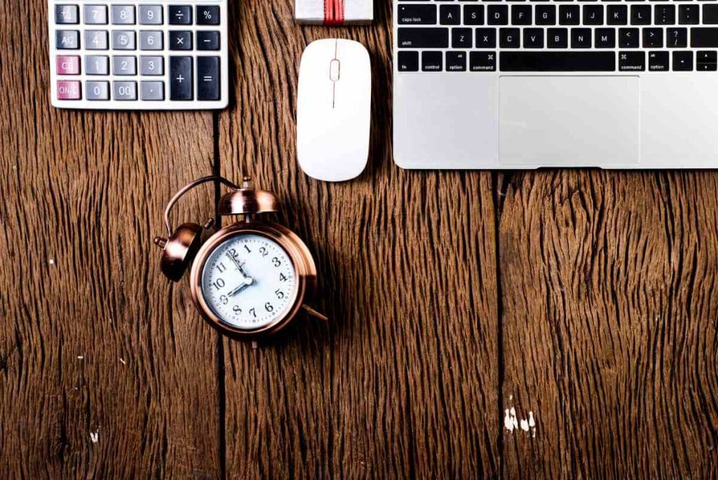 laptop and alarm clock on top of a wooden desk