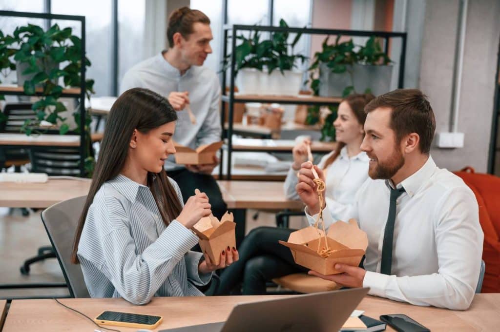 coworkers are eating food from eco boxes in the office together