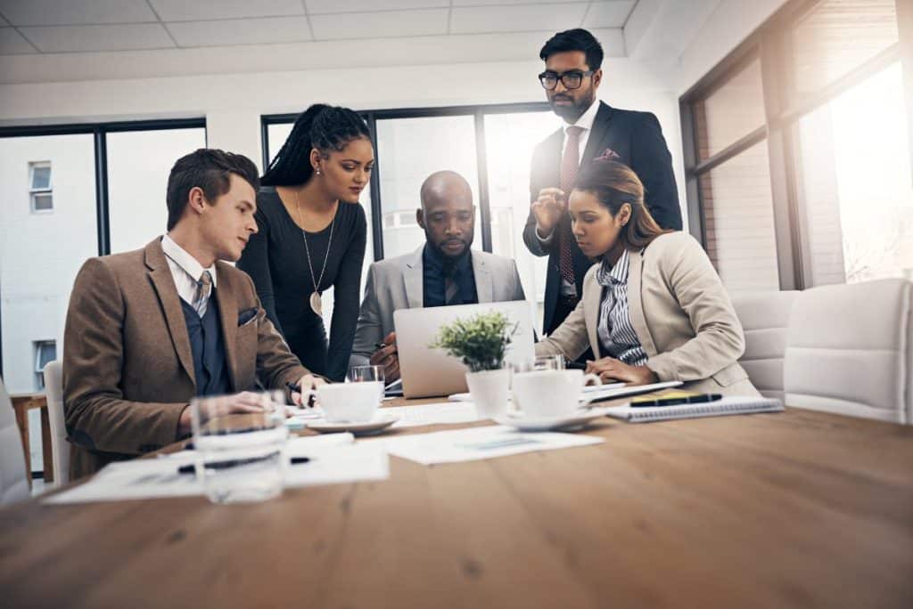 Group of diverse professionals brainstorming and collaborating on a project using sticky notes in a modern office setting